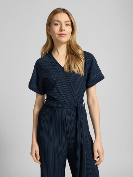 Modelka nosi granatowy Jumpsuit mit Plisseefalten und Bindegürtel Modell 'Pe44arl' od ZABAIONE, krój slim fit, dekolt V, pasek, zbliżenie na górę.