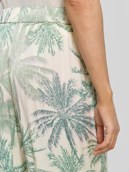 Frauenmodel trägt Regular Fit Weite Hose aus reiner Viskose von s.Oliver BLACK LABEL mit Palmenprint in Grün und Beige, Nahaufnahme Hüfte.