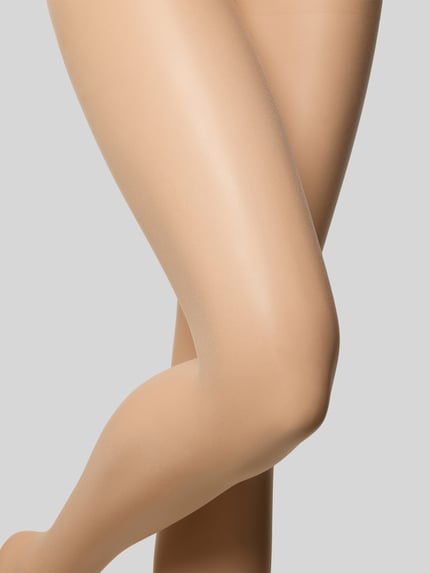 Frauenmodel trägt hauttonanpassende Strumpfhose mit elastischem Bund von Falke, körpernahe Passform, transparent, Nahaufnahme Beine.