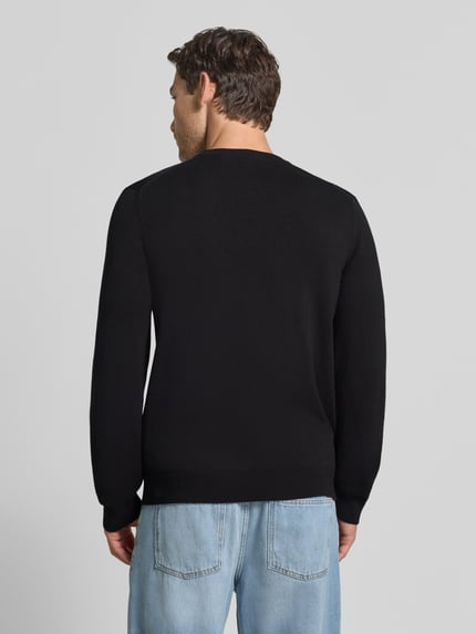 Männermodel trägt schwarzen Regular Fit Pullover aus Baumwoll-Mix von Lacoste, kombiniert mit hellblauer Jeans, Ganzkörperansicht Rückansicht. Herren Pullover von Lacoste.
