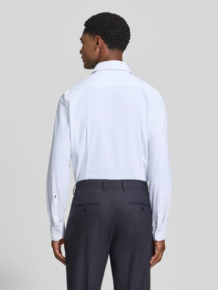 Mężczyzna nosi Slim Fit Businesshemd mit Cutaway-Kragen von Seidensticker, białe koszule biznesowe, widok całej sylwetki z tyłu.