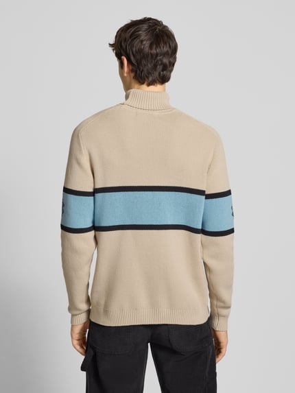 Männermodel draagt Strickpullover met rollkragen van Pegador in beige met blauwe en zwarte strepen, katoenmix, rugaanzicht, regular fit.