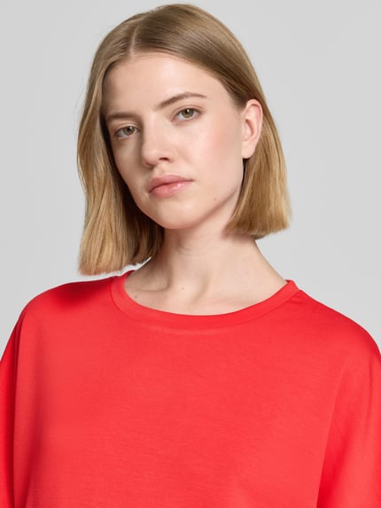 Frauenmodel trägt T-Shirt mit Rundhalsausschnitt Modell 'BANU' von Soyaconcept in leuchtendem Rot, glatte Textur, Nahaufnahme Oberkörper. Damen T-Shirt mit Relaxed Fit, Material-Mix mit Modal-Anteil.