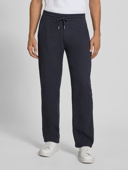 Mężczyznamodel nosi Straight Fit Sweatpants in Musselin-Optik od Lindbergh, ciemnogranatowe, bawełna, muślin, elastyczny pas z tunelem, szerokość w rozmiarze M: 41 cm, długość wewnętrzna nogawki: 81 cm, spodnie z prostymi nogawkami, Ganzkörperansicht von vorne.