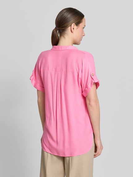Vrouwenmodel draagt Regular Fit Hemdbluse uit pure viscose model 'BUMPY' van Vero Moda, effen roze, afgeronde zoom, borstzakken, rugaanzicht gehele lichaam.
