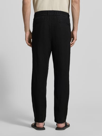 Männermodel trägt Tapered Fit Leinenhose mit Eingrifftaschen von MCNEAL in Schwarz, Paspeltaschen am Gesäß, reine Leinenstruktur, Ganzkörperansicht Rückansicht.