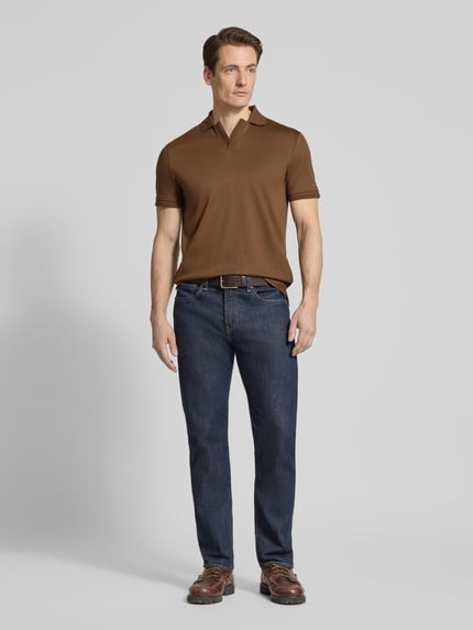 Męski model nosi Regular Fit Poloshirt aus reiner Baumwolle von Tommy Hilfiger, efekt: jednolity kolor, krój regular fit, detal z logo, kołnierzyk polo, dekolt w serek, krótki rękaw, prążkowane zakończenie rękawów, wykończenie z bocznymi rozcięciami, asymetryczny, bawełna; pełen widok z przodu