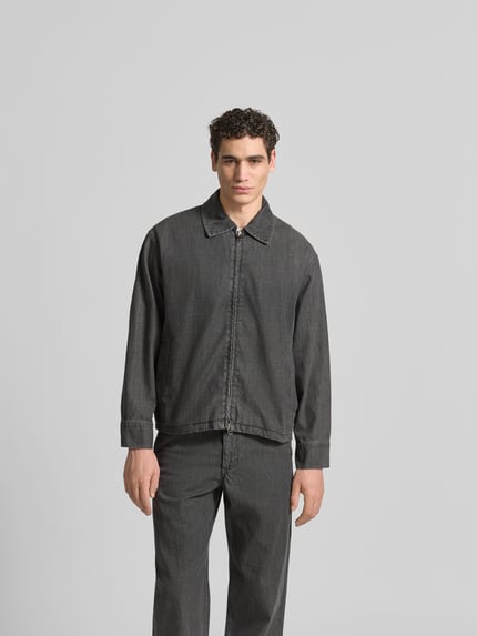 Męski model nosi Regular Fit Jeansjacke aus Baumwoll-Mix von ANNARR, denim, zamek błyskawiczny dwustronny, wykładany kołnierz, długość tyłu 70 cm, szerokość w rozmiarze M 54 cm, długość rękawów 65 cm, krój regular fit, kolor szary, gładka faktura, całkowity widok z przodu.