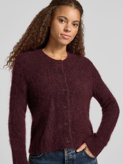 Frauenmodel trägt Cardigan aus Mohair mit Label-Schriftzug von Marc O'Polo, unifarben, Strickoptik, Strukturmuster, Rundhals, Knopfleiste, Regular Fit, gerippte Abschlüsse, Feinstrick, Ganzkörperansicht von vorne.