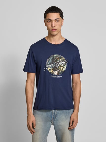 Mężczyznamodel nosi t-shirt z nadrukiem Jack & Jones, bawełna, krój regular fit, model 'HONOLULU', okrągły dekolt, długość tyłu 68 cm, zdjęcie całej sylwetki z przodu.