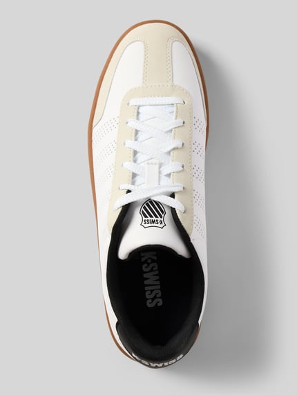 Produktfoto, Sneaker mit Label-Print Modell 'COURT' von K-Swiss in Weiß mit Lochmuster, strukturierter Sohle und Schnürverschluss, abgerundete Form, Gumsohle, sichtbares Branding, Kontext: Herren Sneaker, Absatzhöhe 3 cm, Schafthöhe 7 cm, Schaftweite 10 cm.