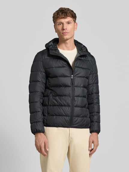 Männermodel trägt Steppjacke mit Kapuze und Reißverschluss von MCNEAL in Schwarz, gesteppte Textur, Eingrifftaschen, Ganzkörperansicht von vorne. Rückenlänge 70 cm, Schulterbreite 46 cm, Brustweite 54 cm, Ärmellänge 63 cm, Regular Fit.