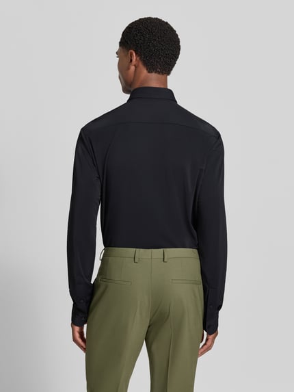 Männermodel trägt schwarzes Slim Fit Businesshemd mit Kentkragen Modell 'P-Roan' von BOSS, kombiniert mit olivgrüner Hose, Ganzkörperansicht Rückansicht, Herren Businesshemd von BOSS.