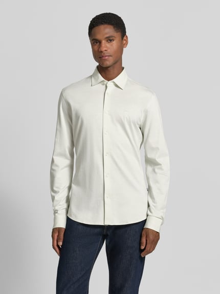 Männermodel trägt weißes Slim-Fit Freizeithemd aus Baumwolle, schlichtes Design, kombiniert mit dunkler Jeans, Modell 'MYSOFT_2' von BOSS Orange, Ganzkörperansicht von vorne.
