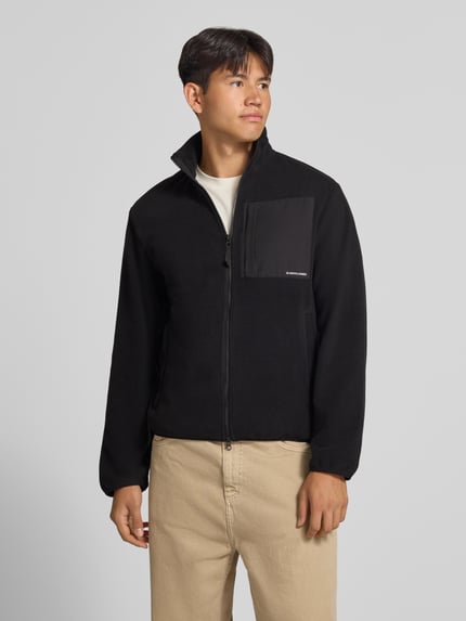 Männermodel trägt schwarze Fleecejacke mit Zweiwege-Reißverschluss Modell 'MASON' von JACK & JONES, Regular Fit, Ganzkörperansicht von vorne.