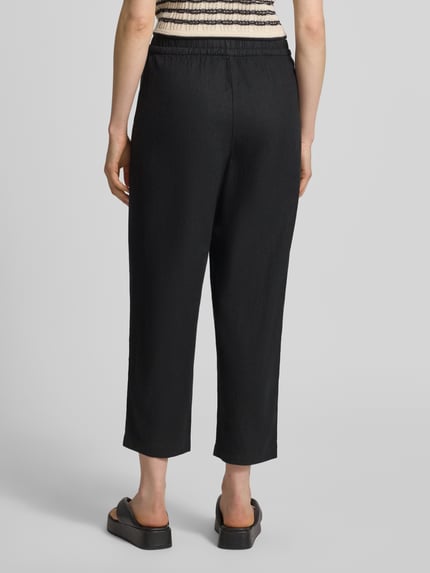 Frauenmodel trägt Leinenhose mit Eingrifftaschen Modell 'LINNO' von ICHI im Leinen-Viskose-Mix, Schwarz, Barrel Fit, elastischer Bund, Ganzkörperansicht Rückansicht.