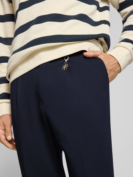 Mannenmodel draagt Straight Fit broek met viscose van Manuel Ritz, elastische materiaalmix, bandplooien, donkerblauw, detailopname. Context: heren broek, knoop- en ritssluiting, bandwijdte maat 50: 42 cm, binnenbeenlengte maat 50: 73 cm.