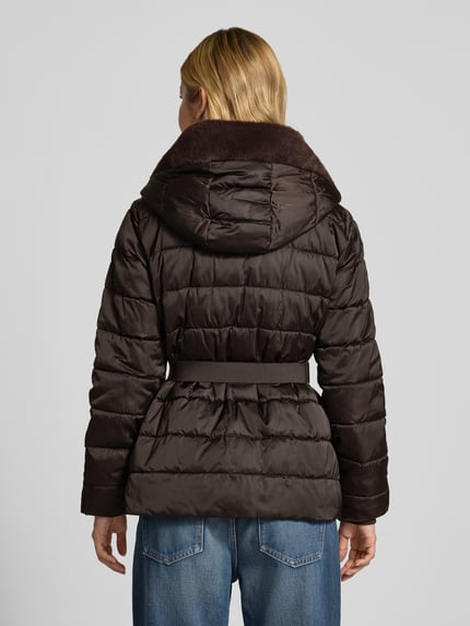 Männermodel trägt Steppjacke mit Reißverschlusstaschen und Gürtel von monari, braun, glänzende Oberfläche, krój slim fit, Ganzkörperansicht Rückansicht, długość tyłu w rozmiarze 36: 67 cm, szerokość ramion w rozmiarze 36: 42 cm, szerokość klatki piersiowej w rozmiarze 36: 49 cm, długość rękawa w rozmiarze 36: 62 cm