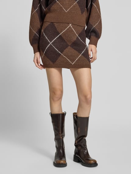 Frauenmodel trägt Minirock mit Argyle-Muster von VERO MODA in Braun- und Beigetönen, Strick-Wollmix, Detailaufnahme Beine.