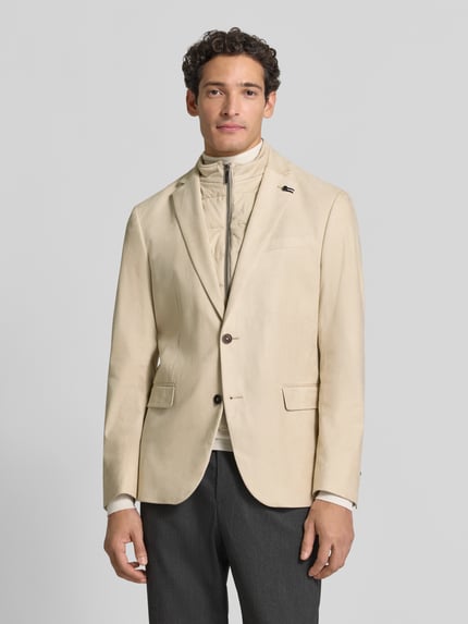 Męski model nosi Regular Fit Sakko aus elastischem Material-Mix mit Label-Detail von bugatti, marynarka elastyczna mieszanka materiałów, krój regular fit, stójka, zamek błyskawiczny, marynarka na 2 guziki, kołnierz z połami, Brustasza, kieszenie z patką, długość tyłu w rozmiarze 50: 74 cm, szerokość ramion w rozmiarze 50: 43 cm, długość rękawów w rozmiarze 50: 66 cm, jasny beż, gładka tekstura, Ganzkörperansicht von vorne.