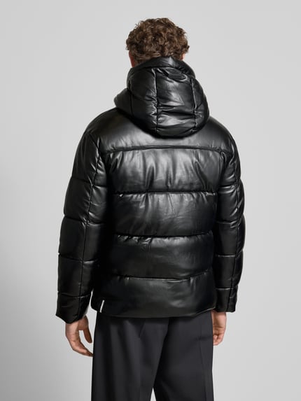 Männermodel trägt Regular Fit Steppjacke mit Logo-Patch Modell 'Coen' von khujo, schwarze Stepp-Optik, Kapuze, Ganzkörperansicht Rückansicht.