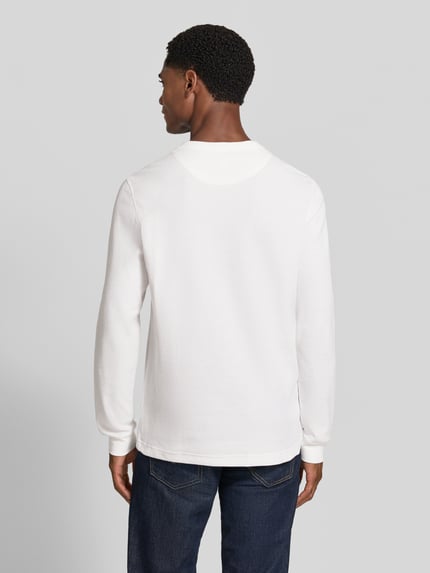 Männermodel trägt Regular Fit Langarmshirt aus reiner Baumwolle von Lacoste in Weiß, glatte Textur, Ganzkörperansicht Rückansicht.