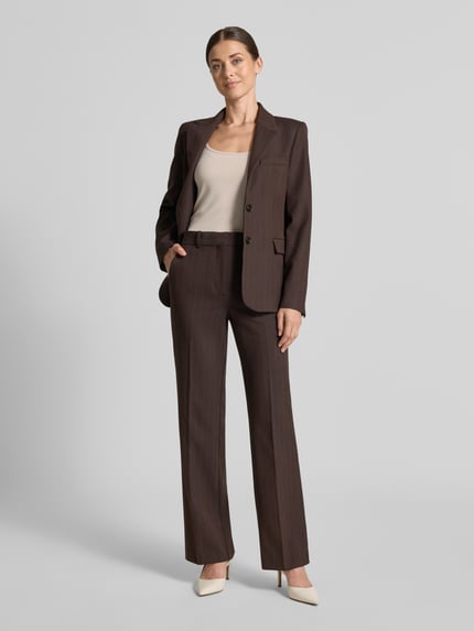 Frauenmodel trägt Flared Anzughose mit Viskose-Anteil Modell 'BERGEN' von MANGO in Braun, glatte Textur, Ganzkörperansicht von vorne.
