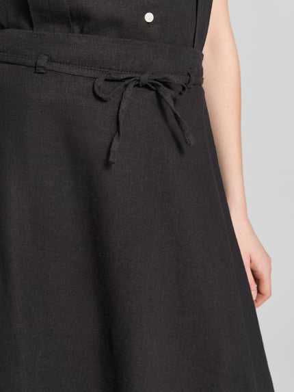 Frauenmodel trägt schwarzen Midirock aus Leinen-Viskose-Mix Modell 'LINNO' von ICHI mit Bindegürtel, Nahaufnahme Oberkörper.