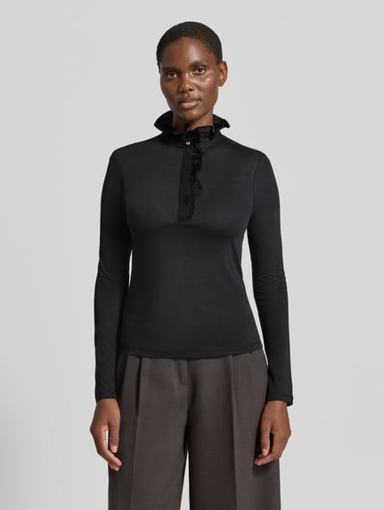 Frauenmodel trägt Longsleeve mit Rüschen von Rich & Royal, Schwarz, taillierter Schnitt, Lyocell-Baumwoll-Mix, Ganzkörperansicht von vorne.