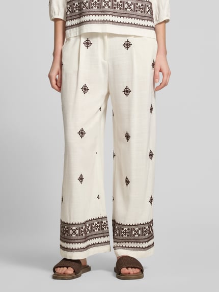 Frauenmodel trägt Hose aus Viskose-Leinen-Mix mit Stitchings von Christian Berg Woman Selection, cremefarben mit braunen Mustern, Regular-Fit, elastischer Bund, Bundweite bei Größe 36: 39 cm, Innenbeinlänge 69 cm, Nahaufnahme Unterkörper von vorne.