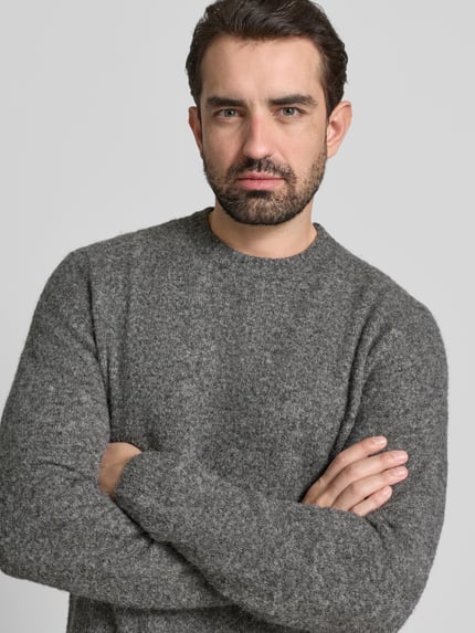 Männermodel trägt Strickpullover mit gerippten Abschlüssen Modell 'BLASIMON' von Jack & Jones Premium, Material-Mix mit Woll-Anteil, lockerer Schnitt, Rundhalsausschnitt, Nahaufnahme Oberkörper.
