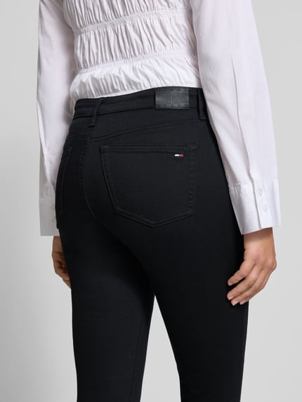 Kobieta nosi czarne, gładkie spodnie Skinny Fit Jeans aus Baumwoll-Mix Modell 'NORA' od Tommy Jeans, widok z tyłu, damskie jeansy marki Tommy Jeans