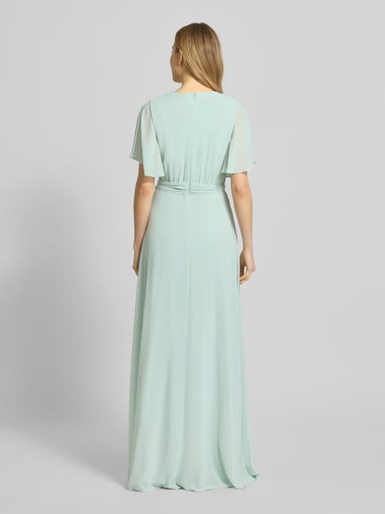 Frauenmodel trägt Regular Fit Abendkleid mit V-Ausschnitt von Christian Berg Cocktail in Pastellgrün, fließender Stoff, Rückansicht Ganzkörperansicht.
