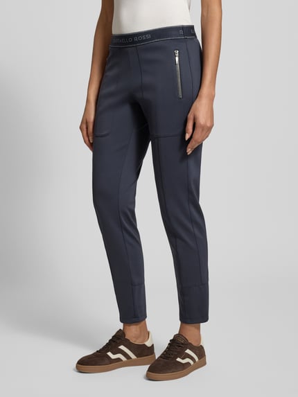 Frauenmodel trägt Stoffhose in verkürzter Passform Modell 'CORRY' von Raffaello Rossi, Material-Mix mit Stretch-Anteil, elastischer Logo-Bund, Reißverschlusstaschen, gerader Schnitt, Farbe Dunkelblau, Ganzkörperansicht von vorne.