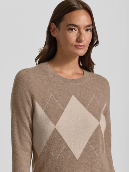 Kobiece modelka nosi Slim Fit Strickpullover aus Kaschmir-Mix mit Rundhalsausschnitt von Christian Berg Woman, Okrągły dekolt, krój slim fit, mieszanka kaszmiru, prążkowane wykończenia, krój z długim rękawem, plisa, imitacja dzianiny, długość tyłu w rozmiarze S 54 cm, długość rękawów w rozmiarze S 63 cm, kolor beżowy z geometrycznym wzorem, gładka tekstura, zbliżenie na górną część ciała