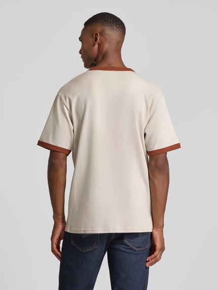 Männermodel trägt T-Shirt mit geripptem Rundhalsausschnitt Modell 'Parker' von Wood Wood, Reine Baumwolle, Lockerer-Schnitt, Rückenlänge 68 cm, Label-Print, Ganzkörperansicht Rückansicht.