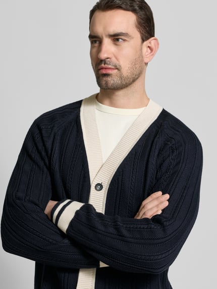 Männermodel trägt Cardigan mit V-Ausschnitt und Knopfleiste von PAUL SMITH, Reine Baumwolle, Regular-Fit, Dunkelblau mit Kontrast, Nahaufnahme Oberkörper.