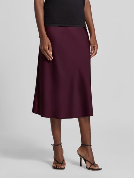 Frauenmodel trägt Midirock mit elastischem Bund Modell 'PELLA' von YAS aus bordeauxfarbenem Satin, A-Linie, Nahaufnahme Oberkörper.
