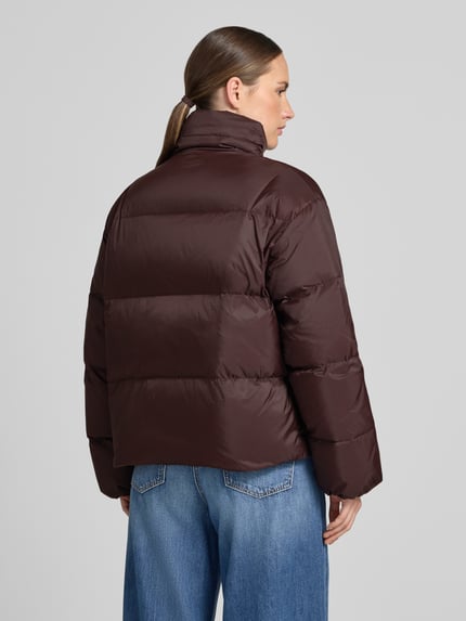 Männermodel trägt Jacke mit Stehkragen und Eingrifftaschen von Closed, prosty krój, zamek błyskawiczny i rzep, wpuszczane kieszenie, długość tyłu w rozmiarze S: 63 cm, szerokość ramion w rozmiarze S: 53 cm, szerokość w klatce piersiowej w rozmiarze S: 61 cm, długość rękawów w rozmiarze S: 60 cm, kolor ciemny brąz, tekstura pikowana, całkowity widok z tyłu.