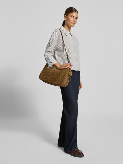 Modelka nosi torebkę damską z prawdziwej skóry model 'NOLITA' od MICHAEL Michael Kors, brąz, szerokość w rozmiarze 38 cm, długość 26 cm, głębokość 10 cm, długość paska na ramię 108 cm, logo, faktura skóry, zamek, widok całej sylwetki z przodu.