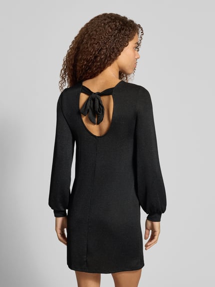 Frauenmodel trägt Langarmshirt mit Glitzerstruktur von ONLY in Schwarz, strukturierter Jersey, hochgeschlossen, geschlitzter Saum, Ganzkörperansicht Rückansicht.