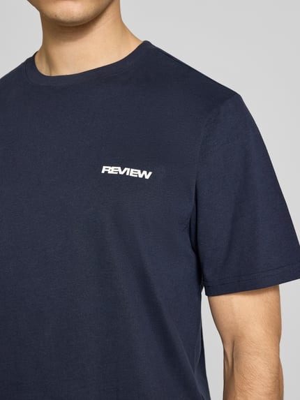 Männermodel trägt T-Shirt mit Logo und Rundhalsausschnitt von REVIEW in Dunkelblau aus Baumwoll-Viskose-Mix, Regular-Fit, Nahaufnahme Oberkörper. Rückenlänge bei Größe M: 64 cm.