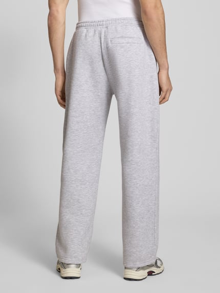 Mannenmodel draagt Sweatpants met elastische band van REVIEW in lichtgrijs, materiaalmix met katoen, relaxed fit, achterzak, binnenbeenlengte maat M 76 cm, volledige lichaamsweergave achteraan.