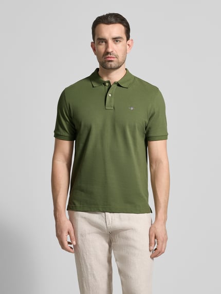 Männermodel trägt Slim Fit Poloshirt mit Logo-Stitching von Gant aus Reine Baumwolle, Polo-Kragen, Kurzärmelig, Ganzkörperansicht von vorne.
