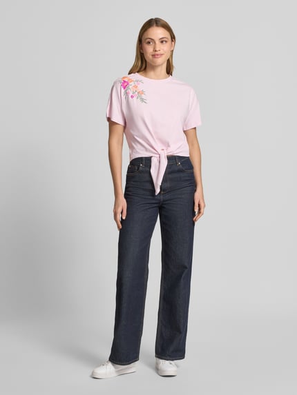 Frauenmodel trägt Damen T-Shirt aus Reine Baumwolle, Regular-Fit, Modell 'Fabian' von YAS mit floralem Stitching und Zierknoten, Ganzkörperansicht von vorne. Rückenlänge bei Größe S: 47 cm.
