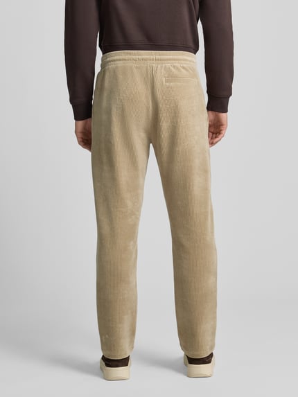 Männermodel trägt Sweatpants mit elastischem Bund von MCNEAL aus beigem Baumwoll-Mix mit Stretch-Anteil, Gesäßtasche, Gerader-Schnitt, Ganzkörperansicht Rückansicht.