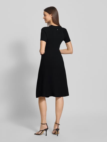 Kobiece model prezentuje czarne, prążkowane knielanges Strickkleid in Ripp-Optik mit 1/2-Arm od ARMANI EXCHANGE, widok całej sylwetki z tyłu, materiał z domieszką wiskozy, fason taliowany, długość do kolan.