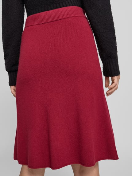 Frauenmodel trägt Knielanger Strickrock mit elastischem Bund von Christian Berg Woman, A-Linie, rote Baumwolle, Ganzkörperansicht Rückansicht.