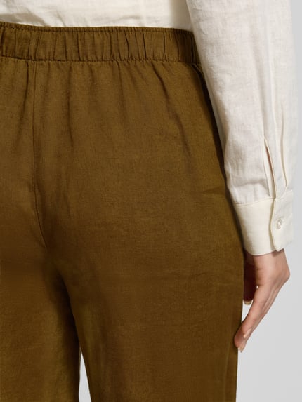 Frauenmodel trägt Leinenhose mit elastischem Bund Modell 'LINO' von Mango aus Reinen Leinen, Relaxed-Fit, Detailaufnahme Rückansicht.