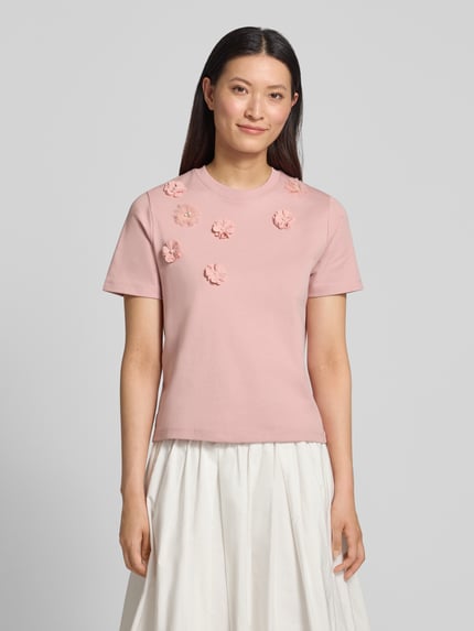 Frauenmodel trägt T-Shirt mit floralen Applikationen von Christian Berg Woman in Rosa, Reine Baumwolle, Gerader-Schnitt, Rundhalsausschnitt, 1/2-Arm, Rückenlänge 52 cm, Ganzkörperansicht von vorne.